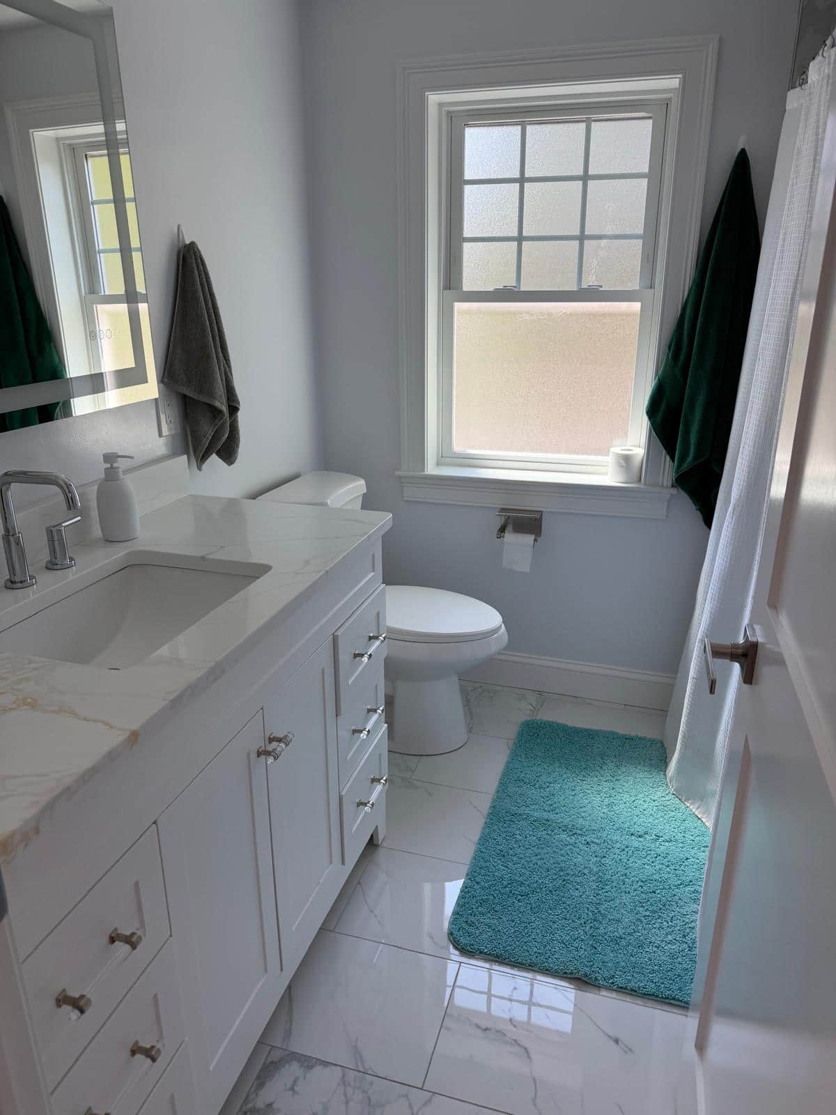 Bathroom with polished marble floor and white vanity after a cleaning visit