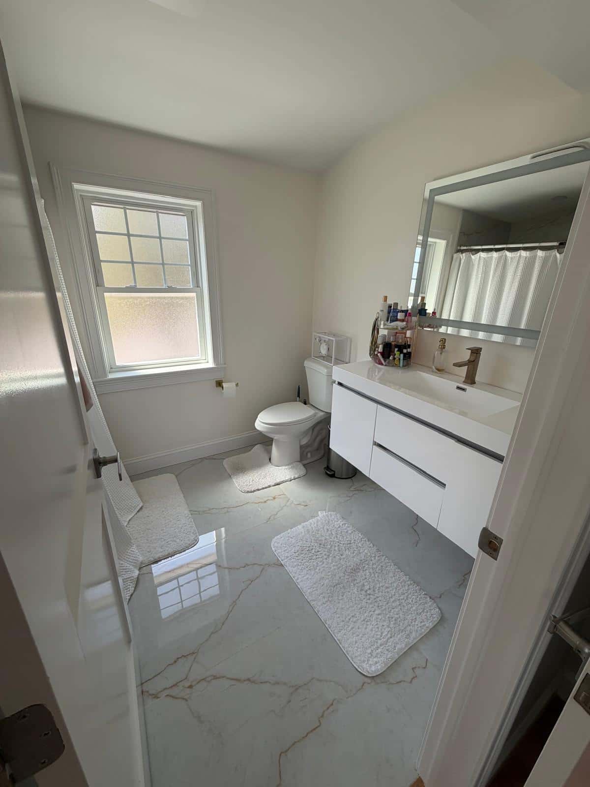 Bathroom with marble tile floor and a white floating vanity after cleaning