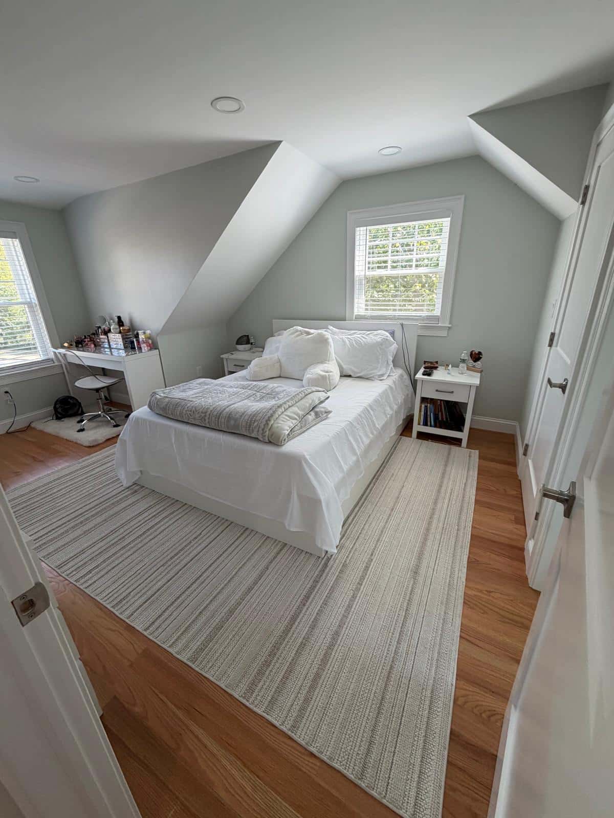 Attic bedroom with dormer ceiling, hardwood floor and a made bed after cleaning