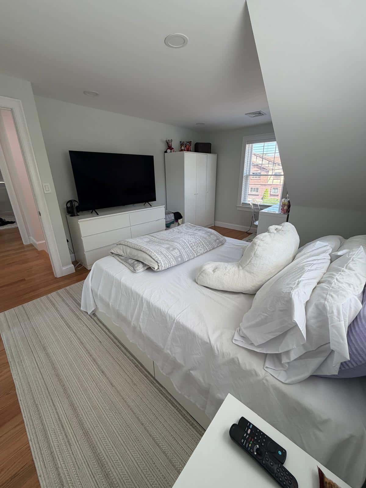 Bedroom with a made bed, striped rug and hardwood floor after a cleaning visit