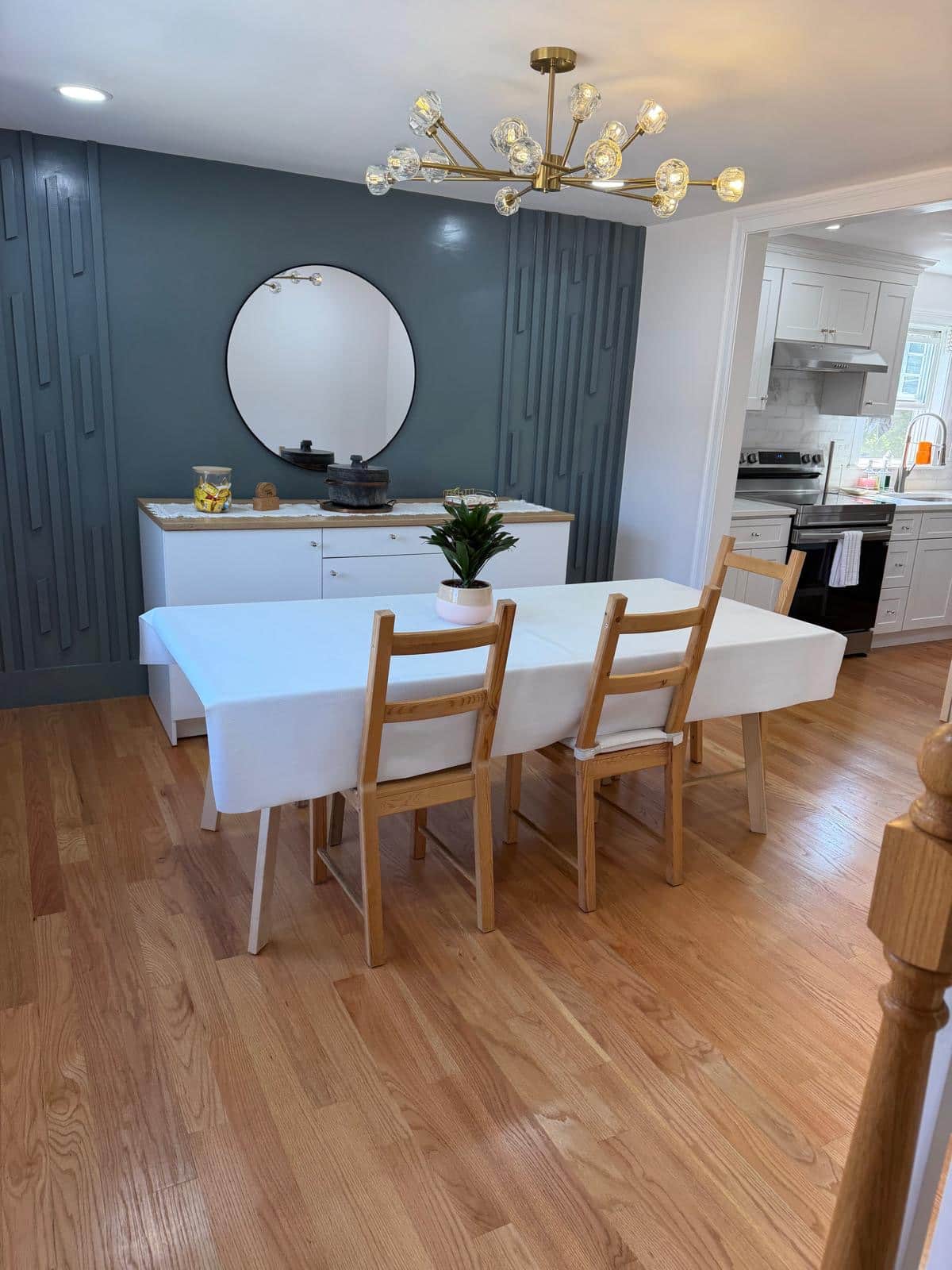 Dining room with teal accent wall, brass chandelier and hardwood floors after cleaning
