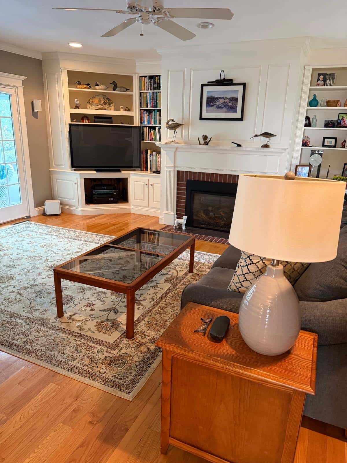 Family room with fireplace, built-in shelves and hardwood floor after a cleaning visit