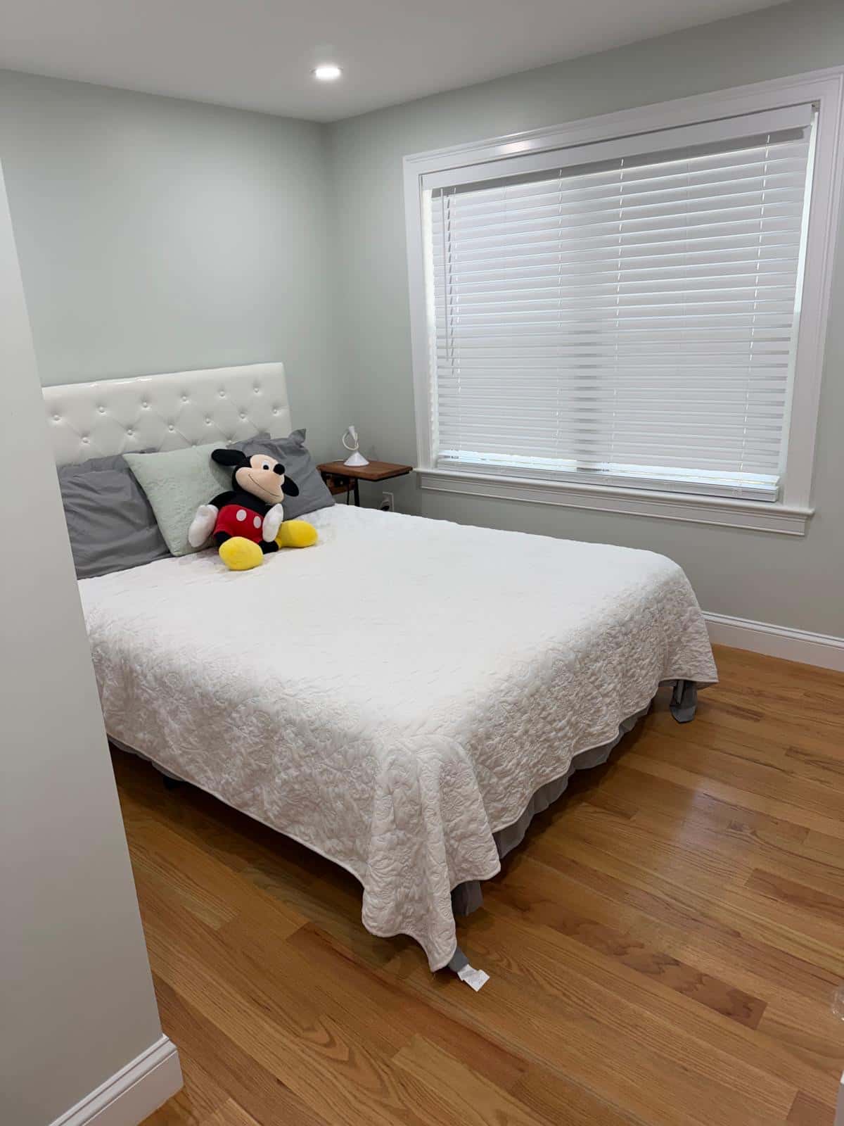 Guest bedroom with a made bed and hardwood floor after a cleaning visit