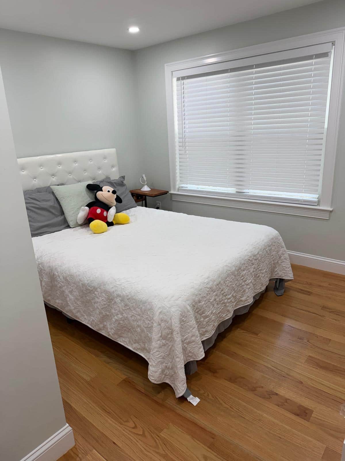 Guest bedroom with a made bed and hardwood floor after a cleaning visit