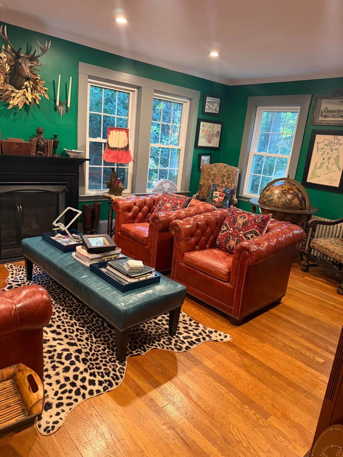 Library with leather chesterfield sofas, green walls and hardwood floors after cleaning